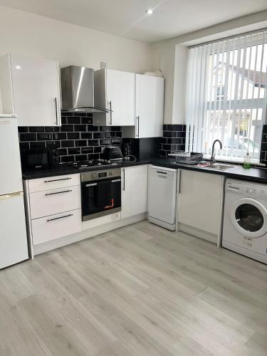 a kitchen with white cabinets and a washer and dryer at Welsh Getaway Apartment 2 - Town Centre in Dowlais