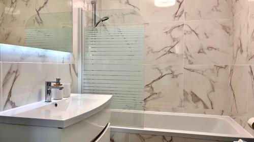 a white bathroom with a sink and a tub at L'Eden - Spacieux 3P Bord de Mer - Juans les Pins in Antibes