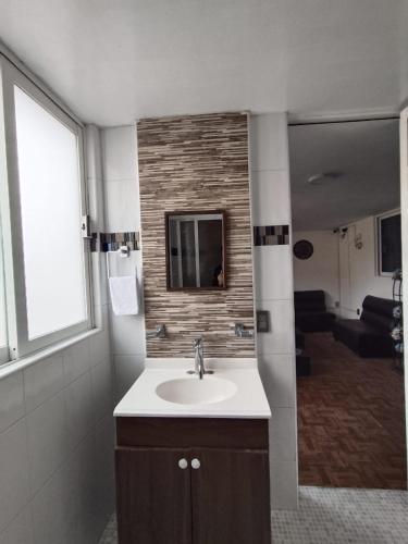 a bathroom with a sink and a living room at Hospedaje Casa Azul in Mexico City
