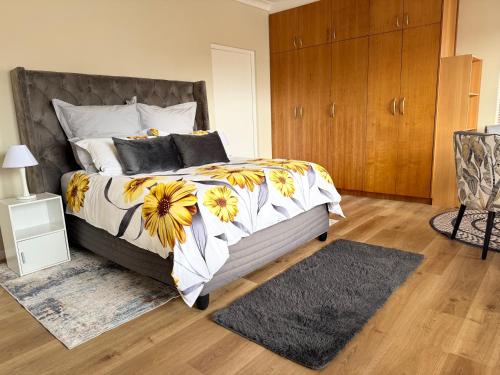 a bedroom with a large bed with yellow and white flowers at Cape Golf Villa in Cape Town