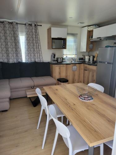 a kitchen and living room with a wooden table and chairs at Mobilhome neuf 3 chambres Oléron in Saint-Denis-dʼOléron