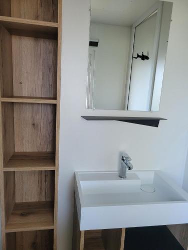 une salle de bain avec un lavabo blanc et un miroir dans l'établissement Mobilhome neuf 3 chambres Oléron, à Saint-Denis-dʼOléron