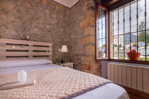 a bedroom with a bed and a stone wall at Apartamentos El Cruce de Moratón in Cóbreces