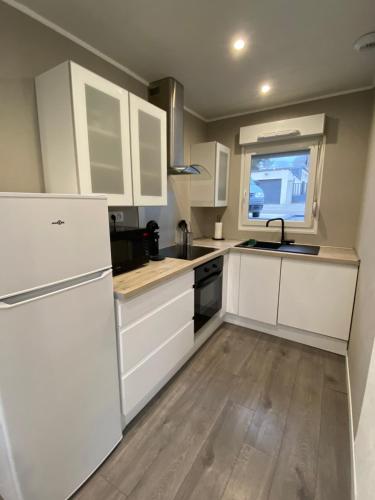 a kitchen with white cabinets and a sink at Maison brantome in Creutzwald-la-Croix