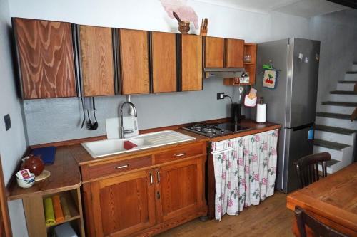 a kitchen with wooden cabinets and a sink and a refrigerator at Casa nella valle in Groscavallo