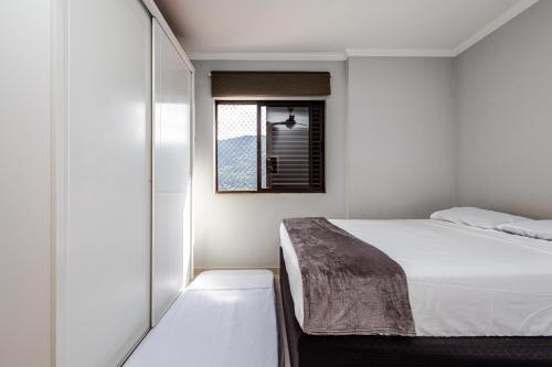 a bedroom with a white bed and a window at Frente mar, wi-fi, estacionamento, smart TV in Praia Grande