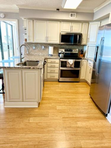a kitchen with white cabinets and stainless steel appliances at The Salty Breeze - 2 Ocean Front Master's - Steps to the Beach in Myrtle Beach
