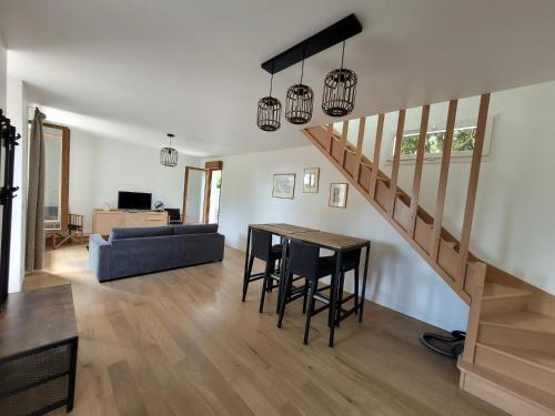 Una sala de estar con una escalera y una mesa y sillas. en La campagne à Paris - Charmante maison à 2 pas de Paris et Versailles, en Garches