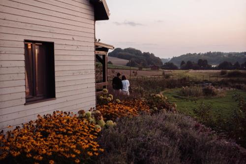 two people standing outside of a building with flowers at Domki na Kaszubach - Chabry i Rumianki - Roztoka, Przywidz - Basen Sauna Jacuzzi KASZUBY in Roztoka