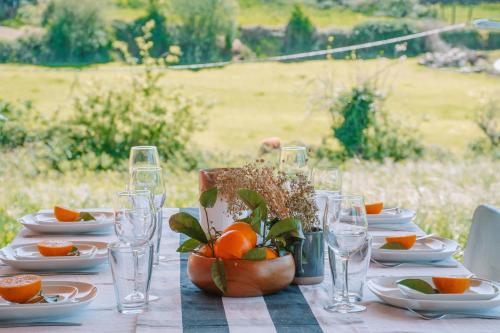 einen Tisch mit Tellern, Gläsern und Orangen darauf in der Unterkunft Just Like Home - Casa Rosa in Padornelo