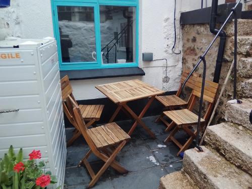 two chairs and a table on a porch with a window at Penzer Cottage in Mousehole