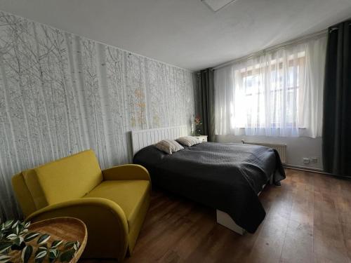 a bedroom with a bed and a yellow chair at Apartmán 2 jeseň-zima in Martin