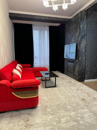 un soggiorno con un divano rosso e una TV di Seven Aparts a Bishkek