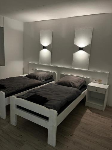 two beds in a bedroom with two lights on the wall at Pension Plesse-Blick Bovenden in Bovenden
