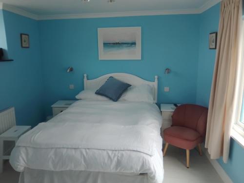 een blauwe slaapkamer met een bed en een rode stoel bij Penzer Cottage in Mousehole