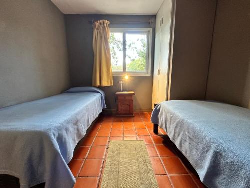 two beds in a room with a window at Los ciruelos - Casas de Motaña in Tafí del Valle