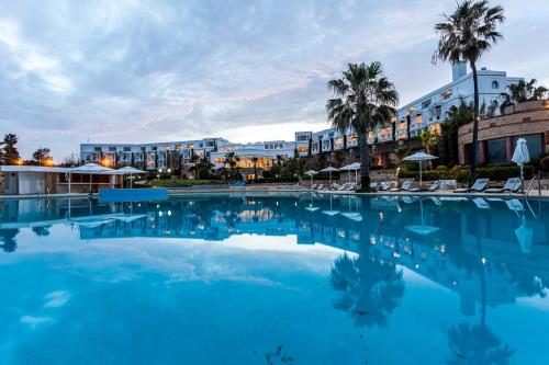 a large swimming pool with palm trees and buildings at Marina Smir Hotel & Spa in M'diq
