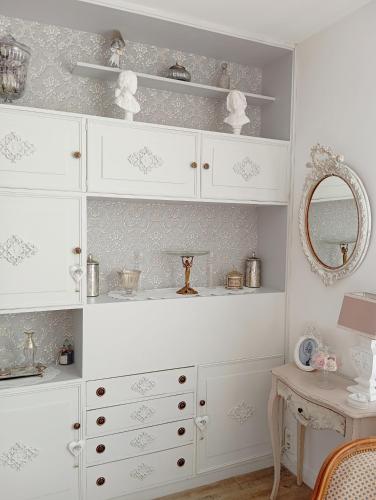 Cette chambre comprend des armoires blanches, une table et un miroir. dans l'établissement Bel appartement, à Montluçon