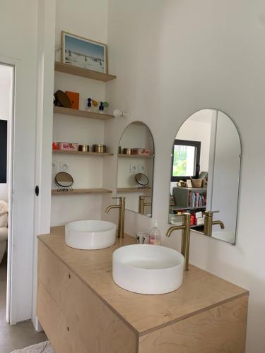 une salle de bain avec deux lavabos et deux miroirs dans l'établissement Maison familiale, à Soorts-Hossegor