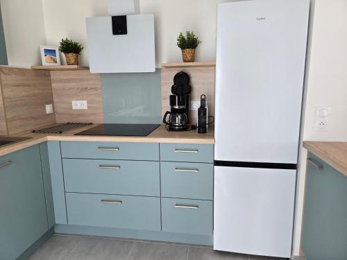 La cuisine est équipée de placards bleus et d'un réfrigérateur blanc. dans l'établissement Chez Patron T4 3BR Oleron, à Saint-Georges-dʼOléron