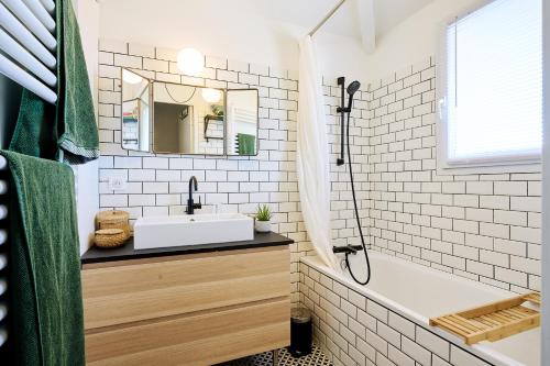 une salle de bain avec un lavabo, une baignoire et un miroir dans l'établissement Maison familiale au calme proche de l'océan, à Ondres