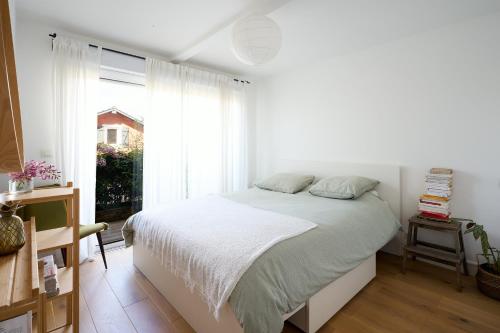 une chambre blanche avec un lit et une fenêtre dans l'établissement Maison familiale au calme proche de l'océan, à Ondres