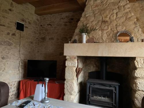 a living room with a stone fireplace and a television at Gîte à la Ruelle "Pierre et Mamie" ! in Savignac-de-Miremont