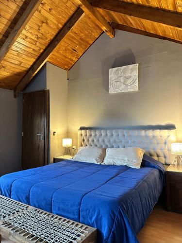 a bedroom with a blue bed and wooden ceilings at Los ciruelos - Casas de Motaña in Tafí del Valle