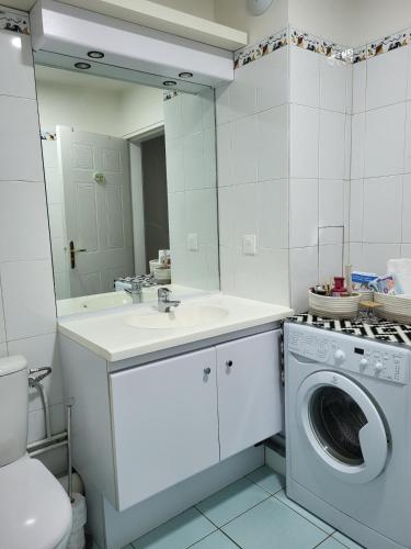 une salle de bain avec une machine à laver et un lavabo dans l'établissement Confort et parking à 10 min de Paris, à Issy-les-Moulineaux