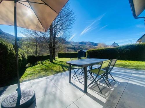 ein Tisch und Stühle auf einer Terrasse mit einem Sonnenschirm in der Unterkunft Maison familiale en montagne - 6 pers - Le Lioran in Saint-Jacques-des-Blats