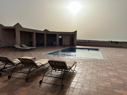 a swimming pool with two chairs in front of a house at Dar Éthiqua in Essaouira