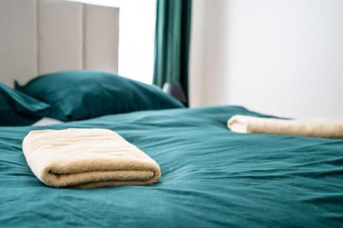 a stack of towels sitting on top of a green bed at Luxapart V Beautiful Views with Breakfast in Košice