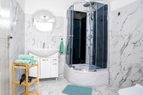 a white bathroom with a shower and a sink at Luxapart V Beautiful Views with Breakfast in Košice