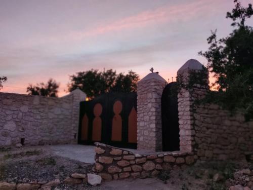 a stone wall with a gate in front of a sunset at Dar Éthiqua in Essaouira