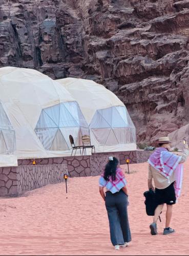 a couple of people standing in front of tents at Wadi rum Bubble Camp & tour in Wadi Rum