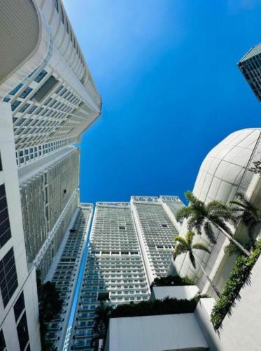 a tall building with palm trees in front of it at Novotel Manila Residence Hotel by Jolly Luxe Suites at Acqua in Manila