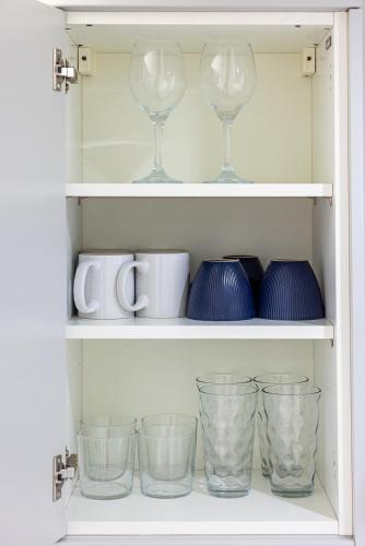 a cupboard with wine glasses and bowls on it at RNM - Business Pro Ready, Private Access Entire Place, Kitchen and bathrooms with all Amenities, Fast WiFi, Smart Tv, Premium Bed, Parking Nearby in Halesowen