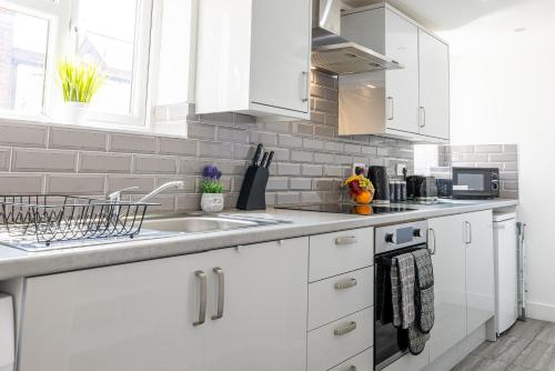 a white kitchen with white cabinets and a sink at RNM - Business Pro Ready, Private Access Entire Place, Kitchen and bathrooms with all Amenities, Fast WiFi, Smart Tv, Premium Bed, Parking Nearby in Halesowen