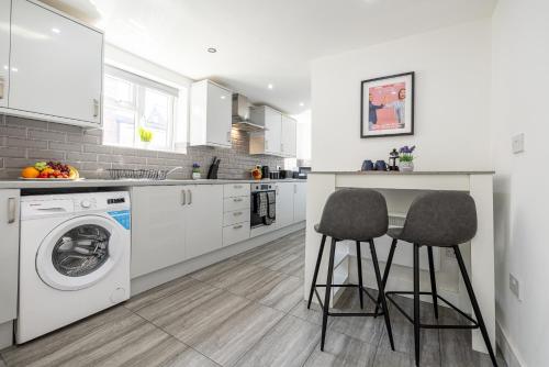 a kitchen with a washing machine and two stools at RNM - Business Pro Ready, Private Access Entire Place, Kitchen and bathrooms with all Amenities, Fast WiFi, Smart Tv, Premium Bed, Parking Nearby in Halesowen