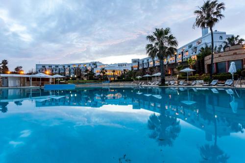 a large swimming pool with palm trees and buildings at Marina Smir Hotel & Spa in M'diq