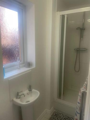 une salle de bain blanche avec un lavabo et une douche dans l'établissement Lim's Cottage, à Armthorpe