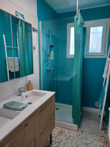 La salle de bains bleue est pourvue d'un lavabo et d'une douche. dans l'établissement Maison Jardin & Garage P2 10 min Gare Nîmes, à Nîmes