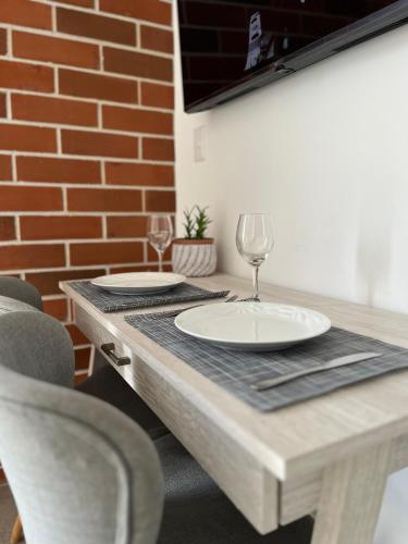 a wooden table with two plates and wine glasses on it at Céntrico apartamento zona 10 in Estación Pamplona