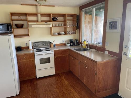 a kitchen with wooden cabinets and a white stove top oven at Seine Boat Inn in Alert Bay