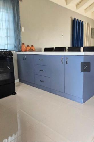 a kitchen with blue cabinets and a stove at The KenEdrice in Kupuis