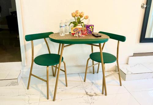 a table with four green chairs and a vase of flowers at Miami Gardens Comfort Suite by Hard Rock Stadium in Miami Gardens