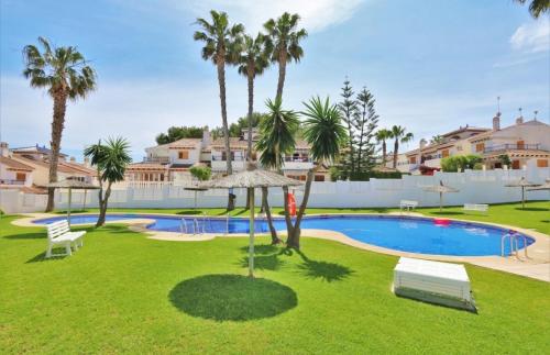 a swimming pool in a yard with palm trees at Chalet adosado en RIOMAR-3, urbanización residencial privada in La Horadada