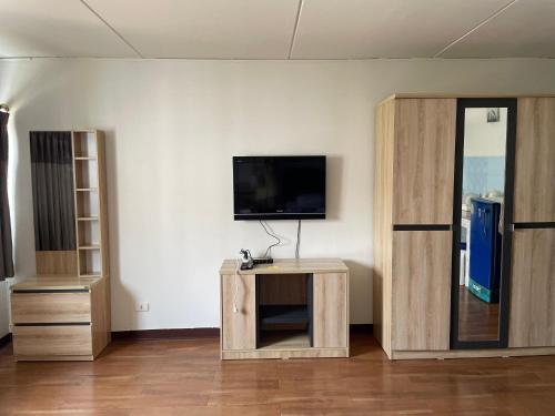 a room with a tv on a wall with wooden cabinets at Dailyroom C3,C4by Anna in Nonthaburi