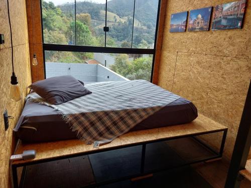 a bed on a platform in a room with a window at Casa Container in Águas de Lindóia