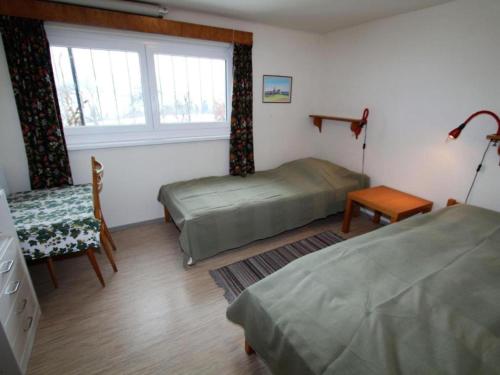 a bedroom with two beds and a chair and a window at Landhaus Karawankenblick in Lukowitz